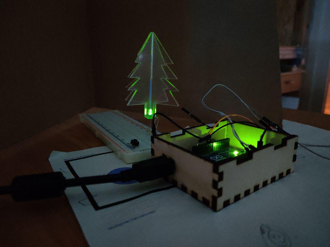 Ein Kind programmiert das Arduino-Projekt "Weihnachtsmelodie" mit leuchtender Acryl-Tanne