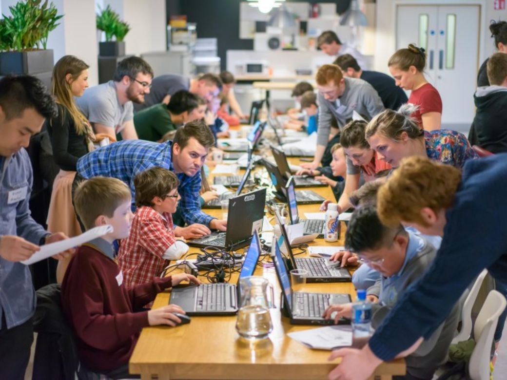 Erwachsene und Kinder arbeiten gemeinsam an Laptops während eines Workshops bei CoderDojo Potsdam